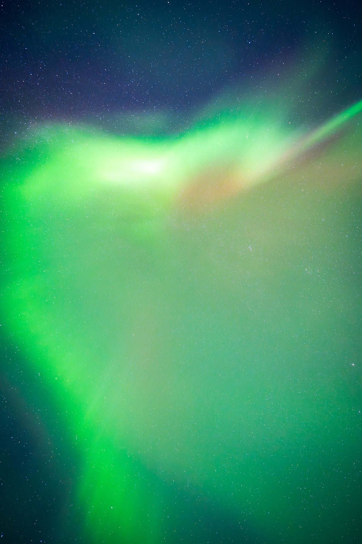 Vibrant aurora borealis with luminous green waves dancing across a starlit night sky, creating an ethereal natural light display.