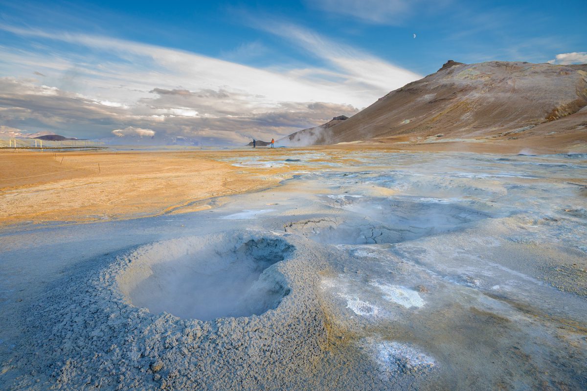 A round bubbling mud pool sits in blue-gray clay amid the warm ochre slopes of the Hverir geothermal field.